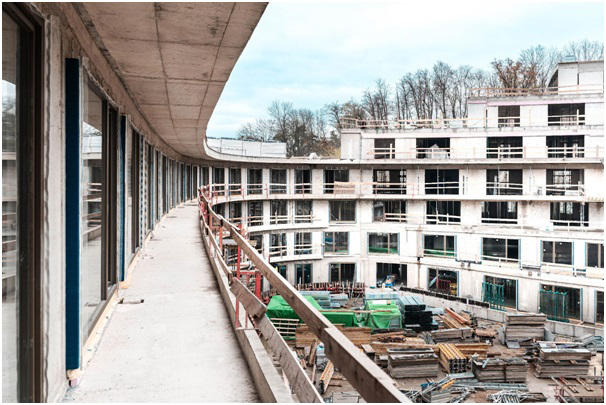 Pohled na vnitřní atrium rozestavěné budovy s balkony a stavebním materiálem.