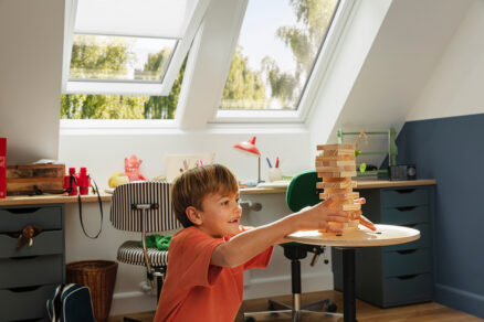 Chlapec hraje deskovou hru v dětském pokoji se střešními okny VELUX, která zajišťují dostatek denního světla.